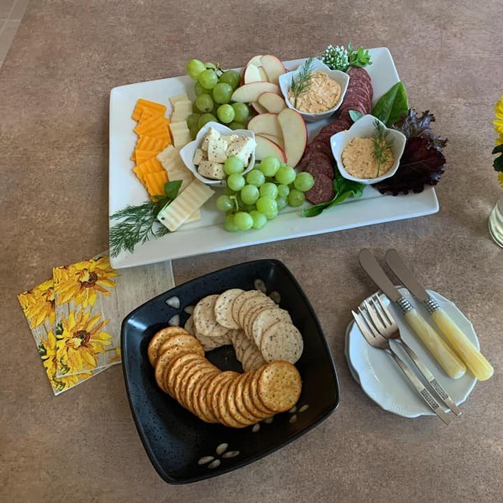 Meat and cheese tray with crackers and yellow bouquet